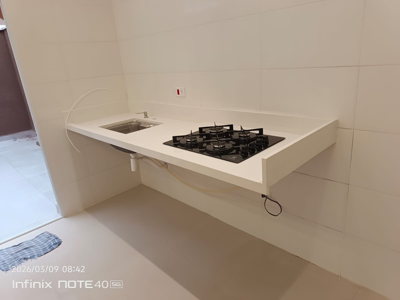 Bancada suspensa Quartzo branco com cuba e cooktop embutidos.